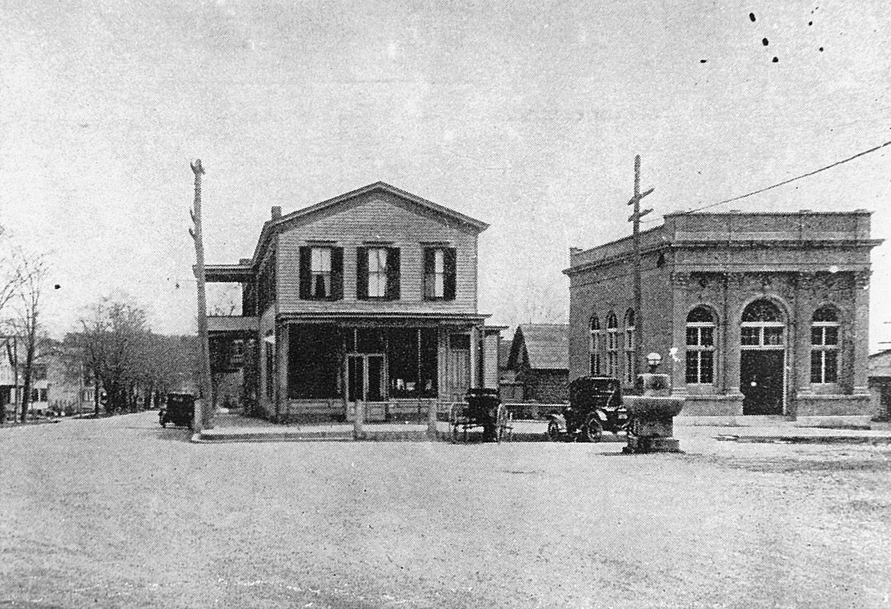 Historic downtown street with early storefronts and automobiles.